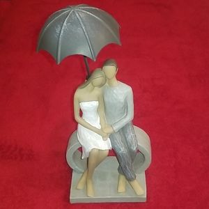 A nice couple sitting in the rain on a bench.